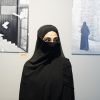 Woman in niqab attending a contemporary art exhibition indoors.